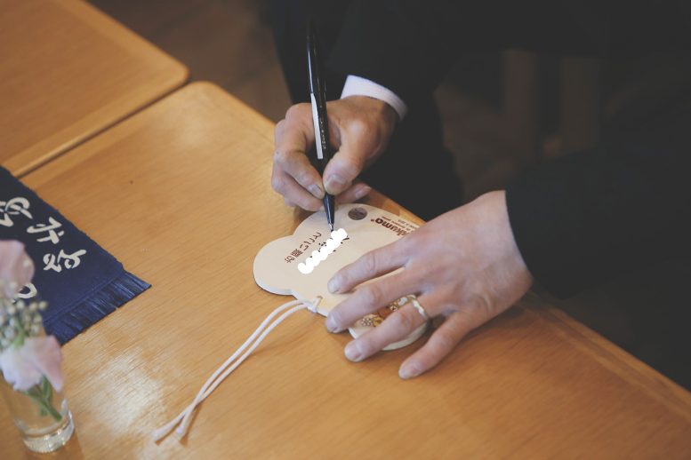 座間神社のリラックマの絵馬に記入するパパさん